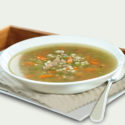 Turkey vegetable soup in a white bowl on a beige napkin
