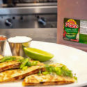 Close up of a quesadilla with salsa, sour cream and lime and a jug of Pace Chunky Salsa